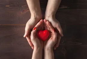 Dos manos sosteniendo un corazón rojo