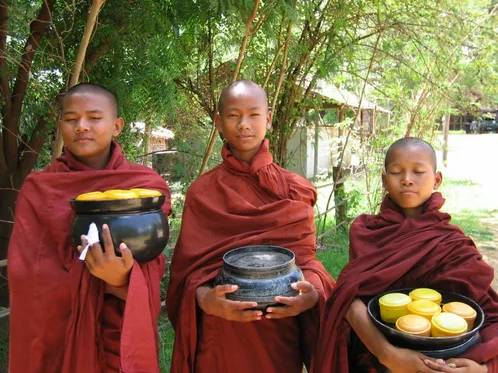 Tres novicios sosteniendo sus cuencos y una ofrenda de limones